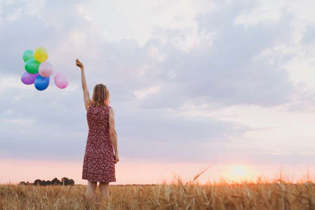 hope concept, emotions and feelings, woman with colourful balloons in the field, backgroundの写真素材