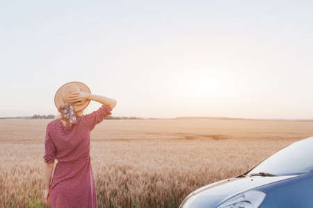 travel by car, summer roadtrip, woman enjoying sunset in the fields near the roadの写真素材