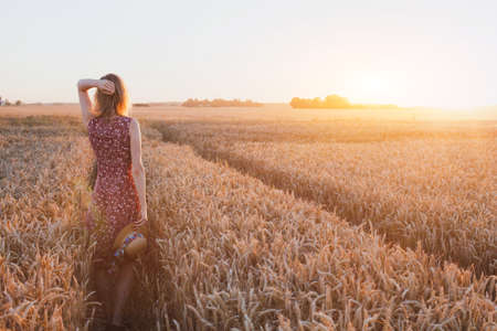inspiration or waiting concept, happy beautiful young woman in sunset field, dreamの写真素材