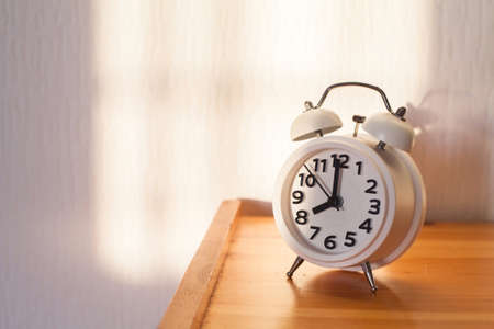 eight o'clock in the morning, alarm clock on bedside tableの写真素材
