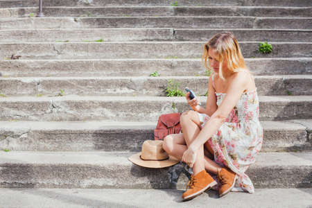 texting on mobile, woman using smartphone app while sitting on the stairs, social networkの写真素材