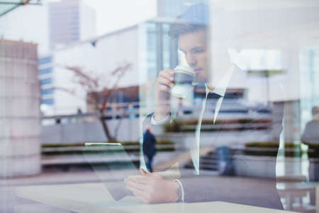 businessman reading news online and drinking coffee in airport cafeの写真素材