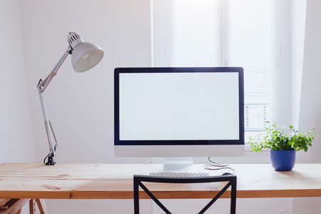 workplace in modern beautiful office, computer with white empty blank screen, scandinavian interior designの写真素材