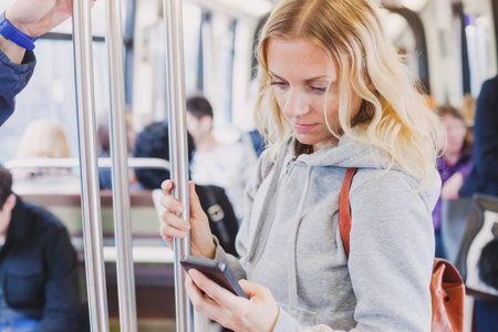 people in metro, commuters, woman passenger looking at the screen of her smartphoneの写真素材