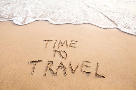 Time to travel, concept text drawn on sand of beachの写真素材