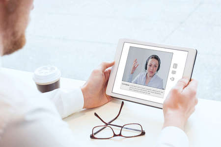 E-learning, video conference, coaching online, man looking at the screen of tabletの写真素材
