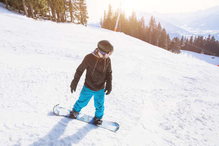 winter holidays, young man on snowboard in alpine mountainsの写真素材