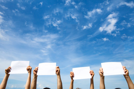 group of people holding empty blank paper signs on blue sky backgroundの写真素材