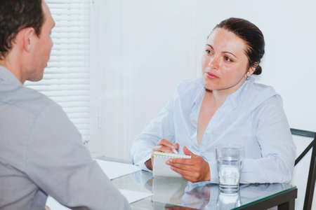 job interview in modern company office, strict woman listening to young manの写真素材