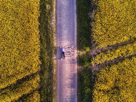 top view of person with bicycle on the road in fields, aerial shotの写真素材