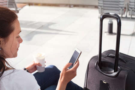 woman passenger using mobile internet or wifi on her smartphone in the airport or modern train stationの写真素材