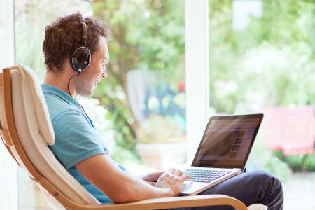 man watching funny videos on internet and laughing at homeの写真素材
