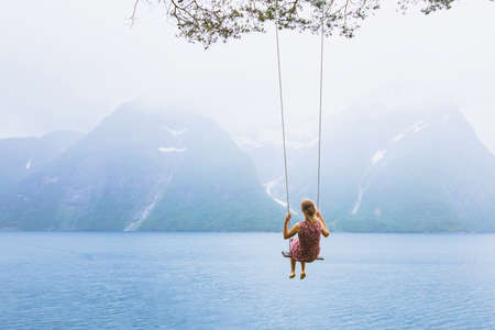 romantic beautiful girl on swing in Norway, happy dreamer, inspiration backgroundの写真素材