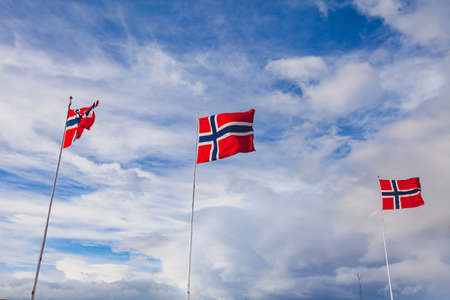 Norway, norwegian flags waving on blue sky backgroundの写真素材