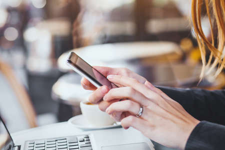 woman hands holding smartphone on city backgroundの写真素材