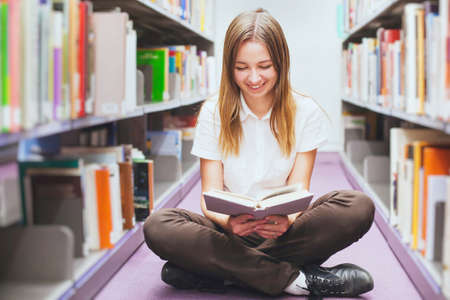student reading book in the library, smiling happy woman, education backgroundの写真素材