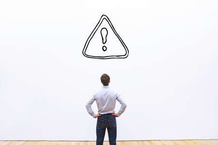restrictions or alert concept in business, businessman looking at danger sign on white backgroundの写真素材