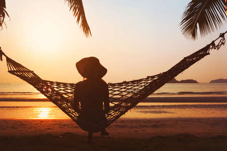 relaxation on the beach, woman in hammock enjoying beautiful tropical sunsetの写真素材
