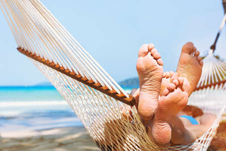 family relaxing on the beach in hammock, exotic holidays travel, closeup of feetの写真素材