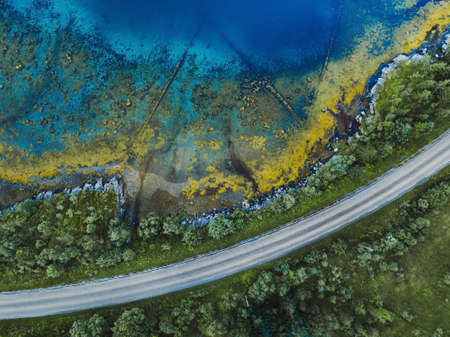 beautiful aerial landscape with pattern of blue water, road and green forest, view from droneの写真素材