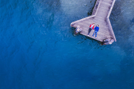 romantic couple lying on the wooden pier on lake with blue water, love and dating concept,...