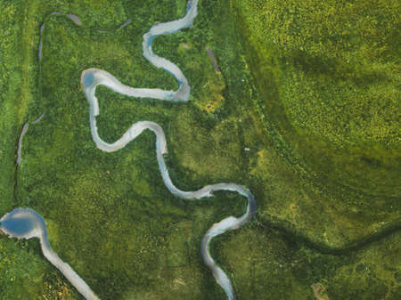 aerial landscape of winding river in green field, top view of beautiful nature texture from droneの写真素材
