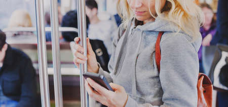 person looking at the screen of smart phone in subway, woman holding mobile in metroの写真素材