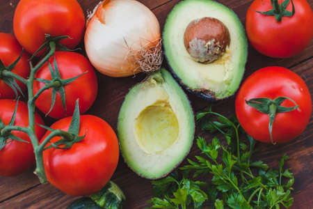 avocado with tomatoes and onion on wooden background, fresh vegetables close upの写真素材