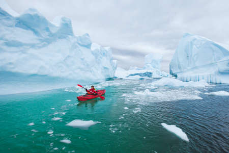 man paddling on kayak between ice in Antractica in Iceberg Graveyard, extreme winter kayaking, polar adventure near Pleneau islandの写真素材