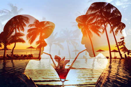 party time double exposure, silhouette of happy couple drinking cocktail together on the beachの写真素材