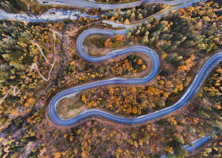 Travel by winding road in autumn forest, aerial landscape of fall season nature.の写真素材
