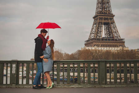 romantic couple in Paris near Eiffel tower in autumn, dating, man and woman kissing under umbrellaの写真素材