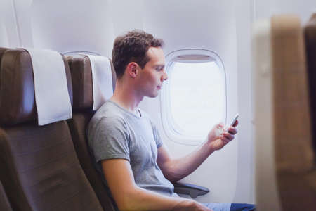 passenger of airplane using mobile smart phone in the plane, travel app on smartphoneの写真素材