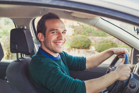 Portrait of happy driver in car. Smiling young man looking at camera who got his driving license.の写真素材