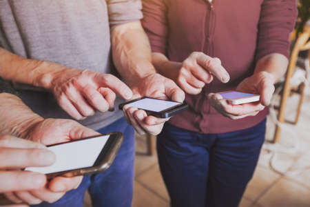 hands of group of people coworkers using smartphones, mobile online communication or social network conceptの写真素材