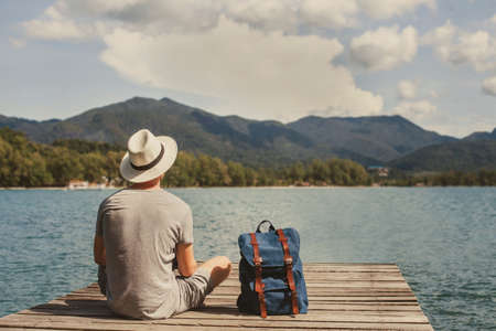 travel, summer holidays, tourist with backpack relaxing on wooden pier, vacation tripの写真素材