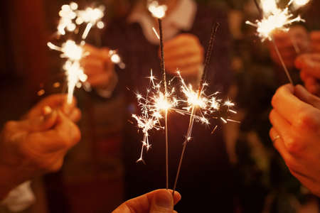 family celebrating christmas holidays, party people holding sparklers, festive lights for new year or birthdayの写真素材