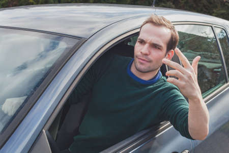 angry driver in the car unhappy and displeased with conflict with other people and trafficの写真素材