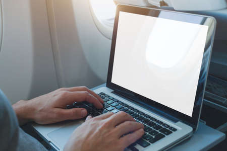 passenger using laptop computer in airplane, onboard wifi internet connection in flight, white empty screenの写真素材