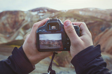 landscape travel photographer hands holding camera, taking photo of mountainsの写真素材