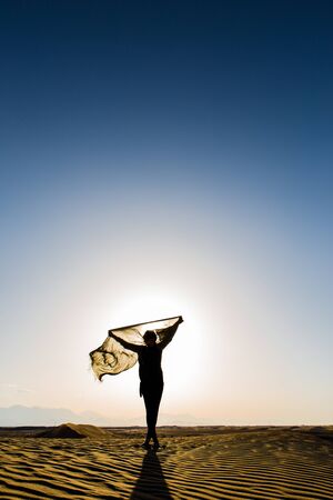 women sihouette with long scarf during sunset in Bafgh desert in Yazd, Iranの写真素材