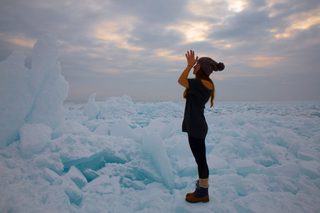 girl in winter time doing yoga at ice hummock in frozen lake Kapchagai near Almaty, Kazakhstan