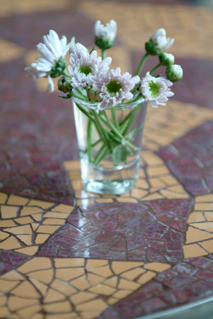 Gerberas in a glass sitting on a beautiful mosaic tableの写真素材