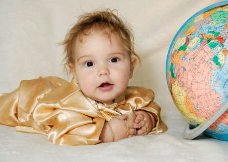 Little curly-headed boy in Chinese garment next to plastic Earth modelの写真素材