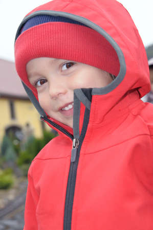 Three year old boy dressed in red against the rain smiles at the cameraの写真素材