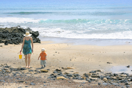 Mother and her two year old boy carrying water from the sea in a toy bucket; Graciosa, Canary islands, Spainの写真素材