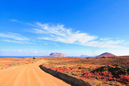 North-Western edge of Island Graciosa with an ancient volcano on the right and Island Montana Clara across the water. There is an ongoing construction of roads from the harbor. Canary islands, Spainの写真素材