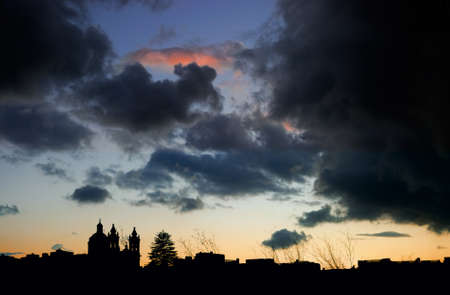 Malta, sunset over Gozo island; silhuette of local church against dramatic skyの写真素材