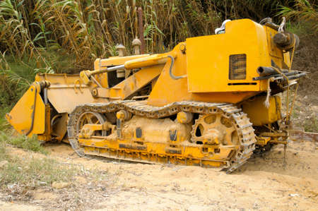 Yellow bulldoser parked on the edge of a dirt trackの写真素材