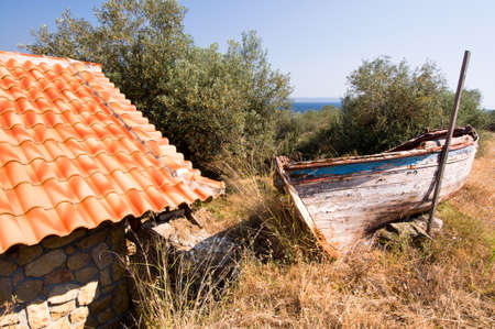 Old fisherman boat next to a shed by olive grove in Greeceの写真素材